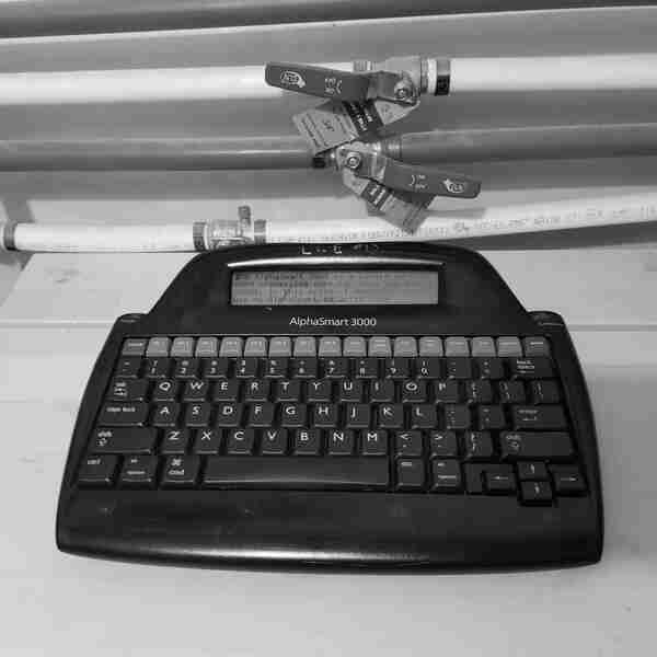 A close-up of an AlphaSmart 3000 displaying the words: "The AlphaSmart 3000 is single purpose word processing computer from the early 2000s. In this note, I'll describe how I use my AlphaSmart to write code"