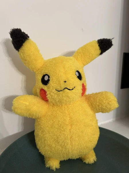 A Pikachu plushie sitting in a green dish.