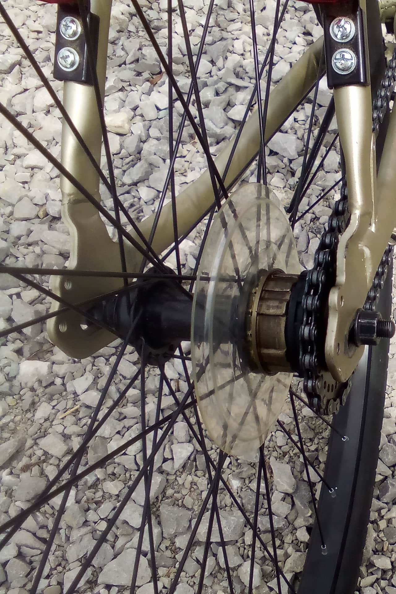 A shot of a bicycle chain from the rear focused on a butchered freewheel with several spacers holding a single gear in place
